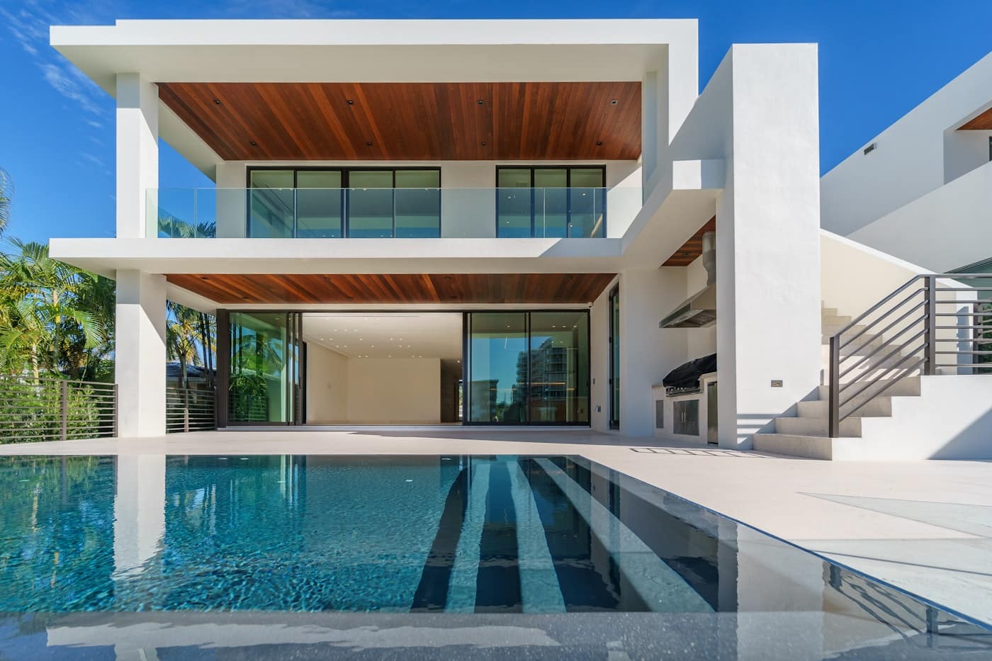Sonsuzluk havuzu ve ahşap kaplamalı tavanlarıyla modern lüks bir villa cephesi